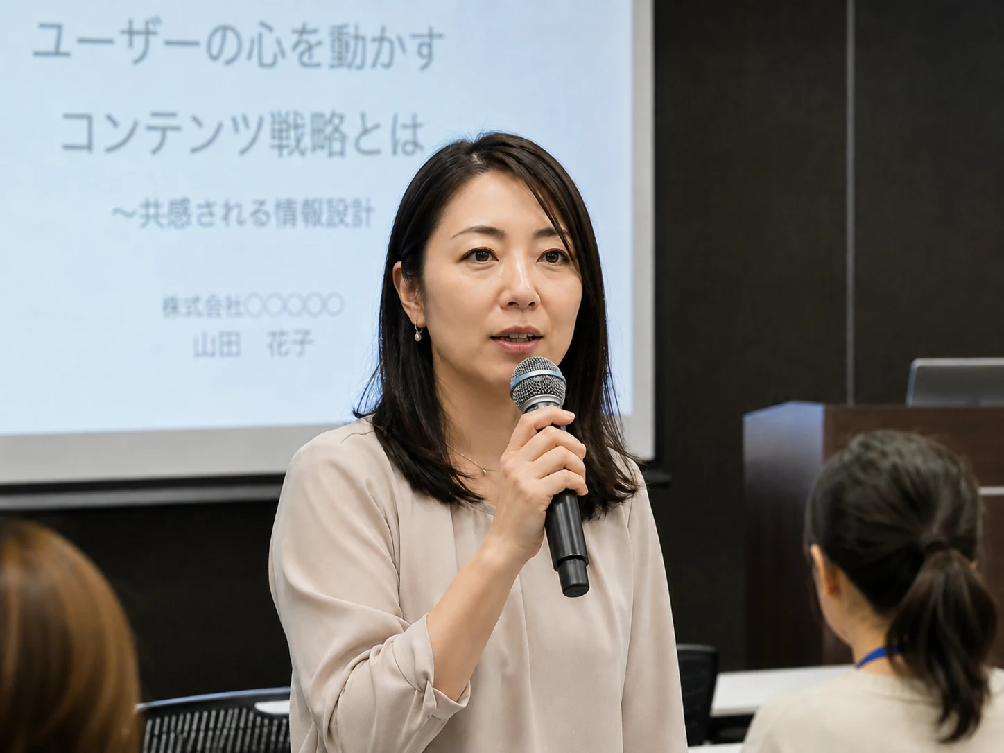 美肌補正ありの日本人女性講師が同じセミナー会場でマイクを持って講演している様子